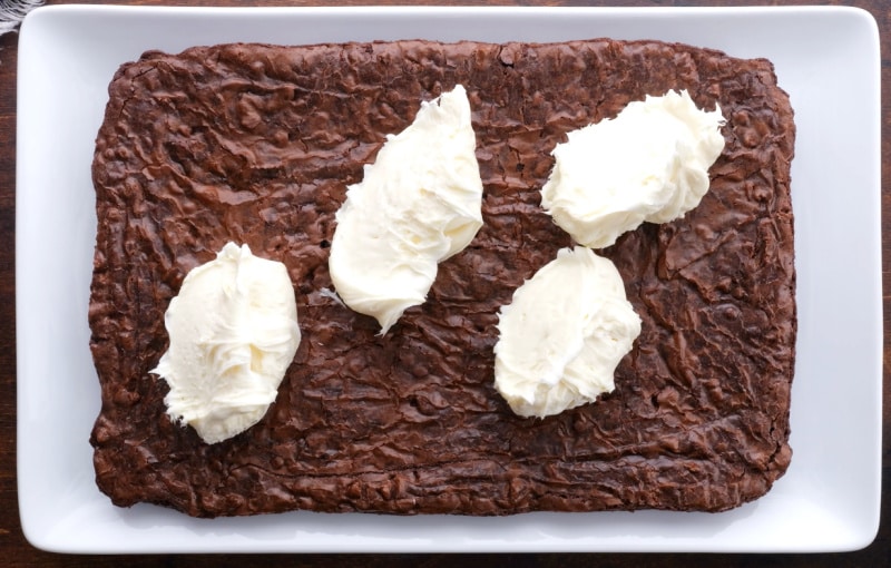 Frosting being spread on brownies.