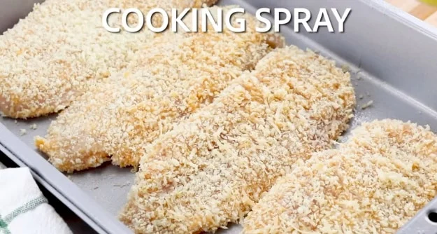 Spraying chicken with cooking spray.