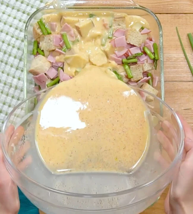 Pouring egg mixture over casserole.