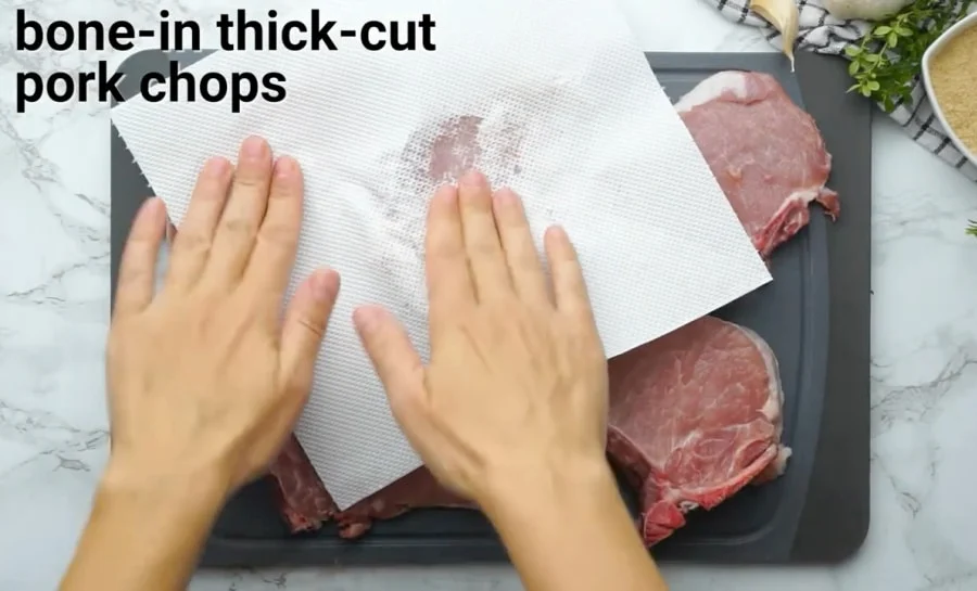 Blotting pork chops dry with paper towels.