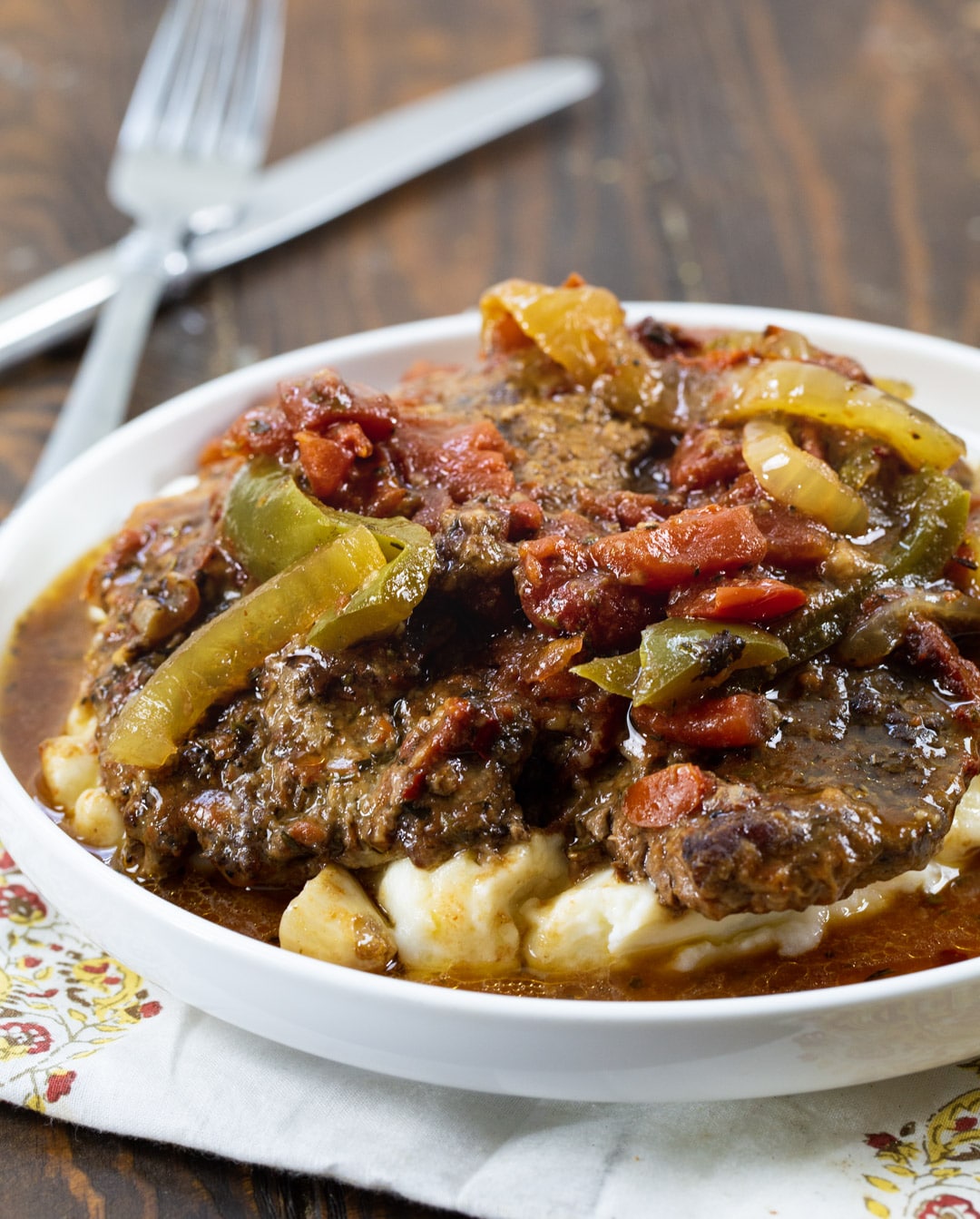 Slow Cooker Swiss Steak serve over mashed potatoes on a plate.