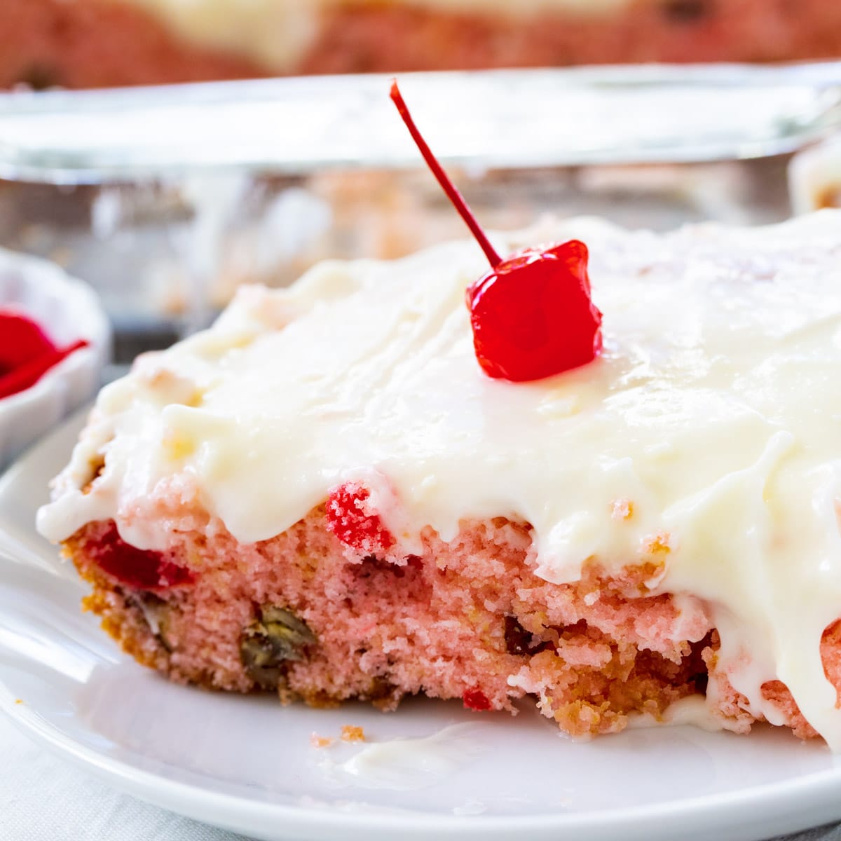 Slice of Cherry Sheet Cake topped with a cherry on a plate.