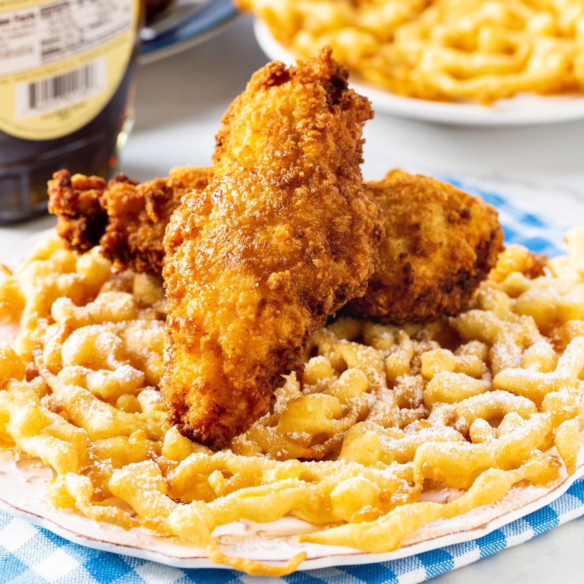 Two fried chicken tenders on top of funnel cake.