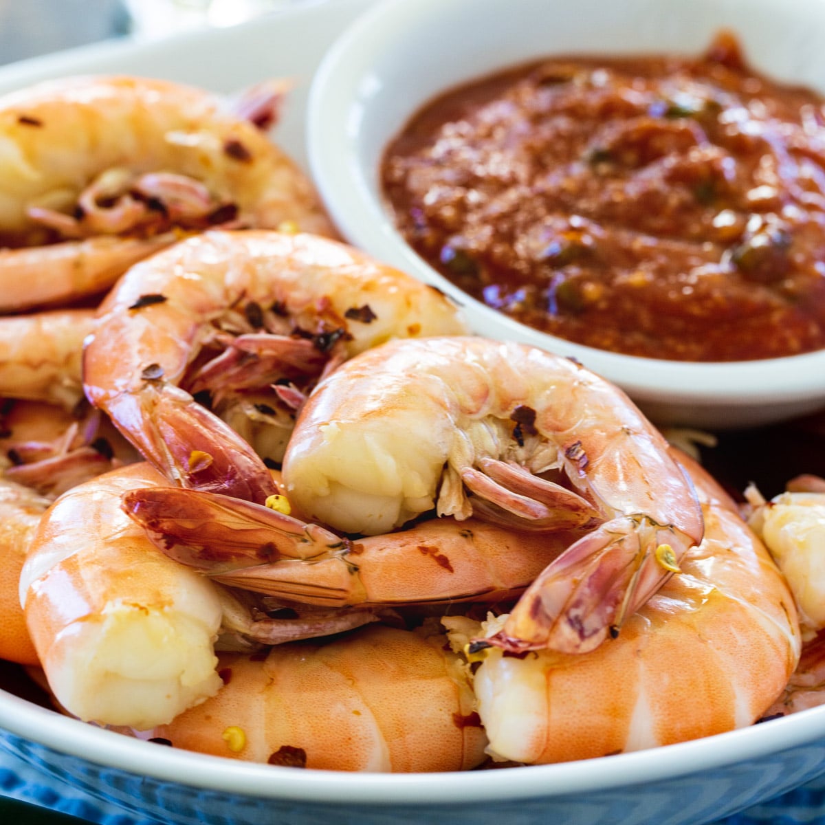 Cooked Shrimp on plate with bowl of cocktail sauce.