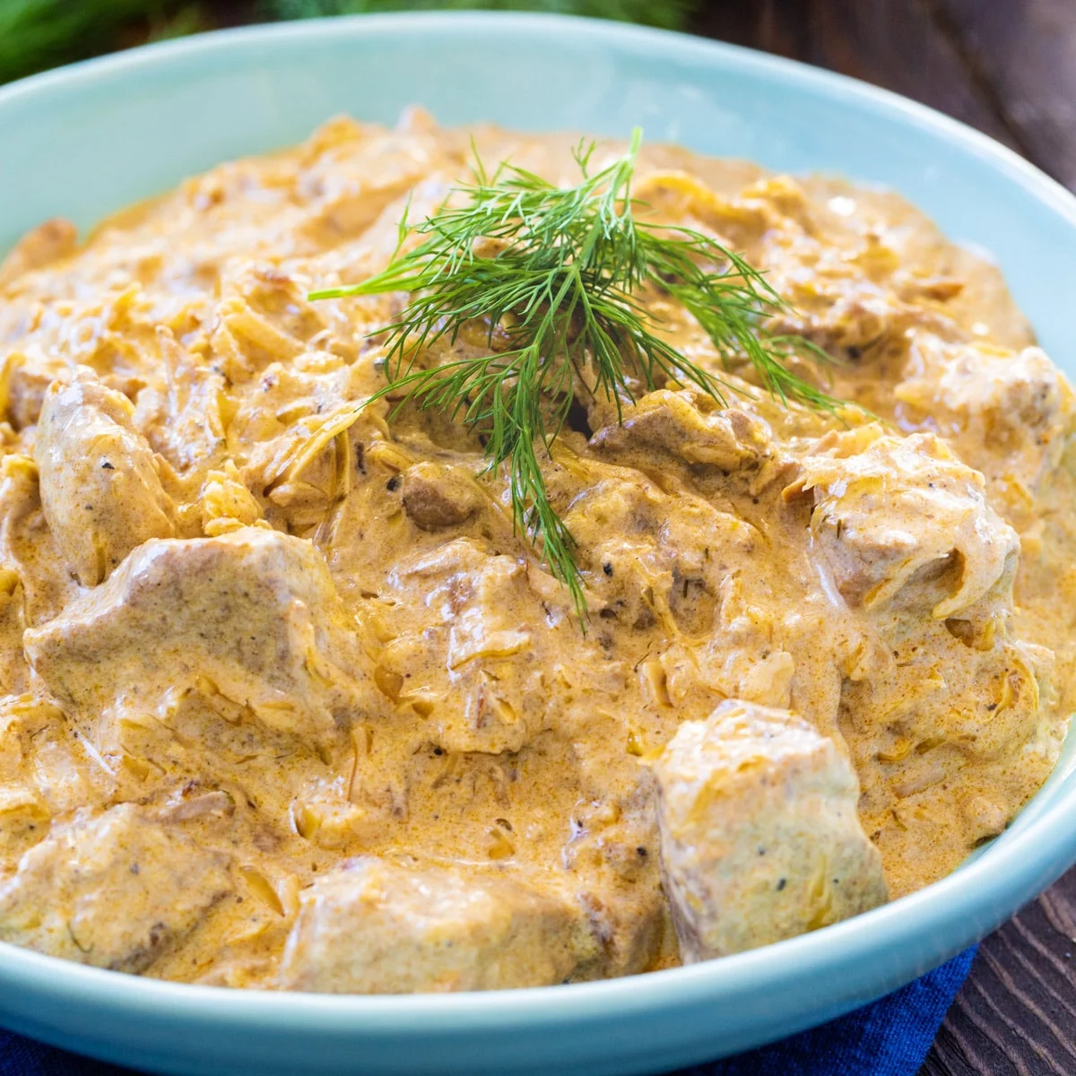 Hungarian Pork Stew topped with dill in a blue bowl.