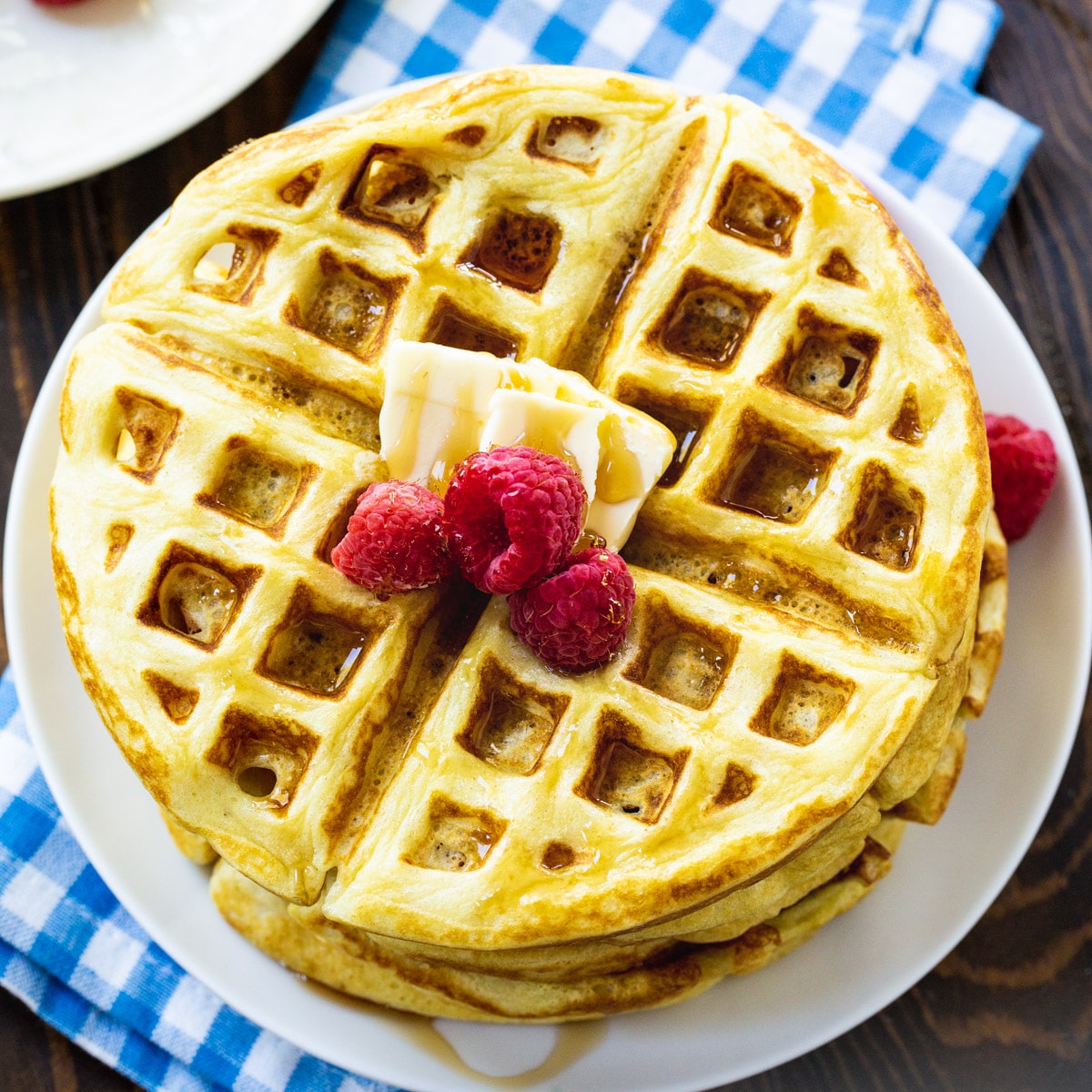 Overhead of stack of Overnight Yeast Waffles topped with butter and raspberries.