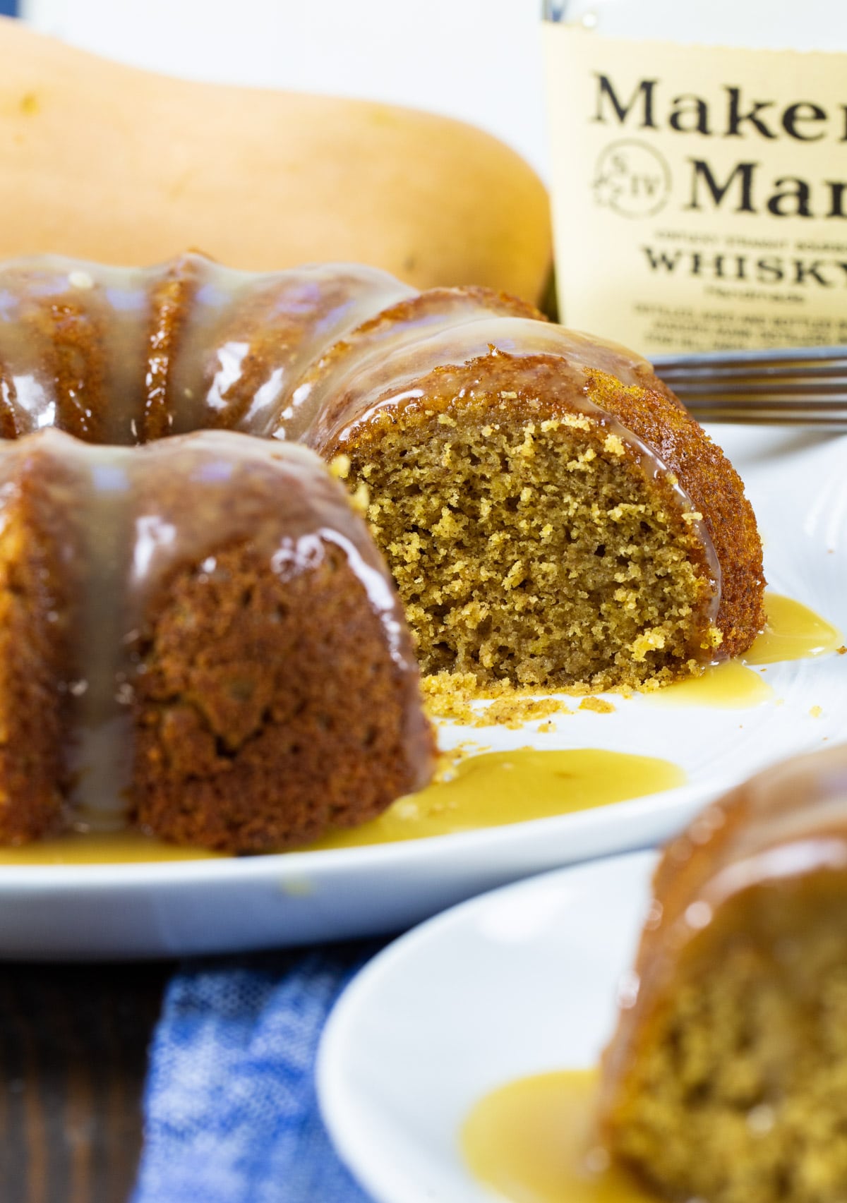 Butternut Squash Cake with Bourbon Glaze with a few slices cut out and bottle of bourbon.