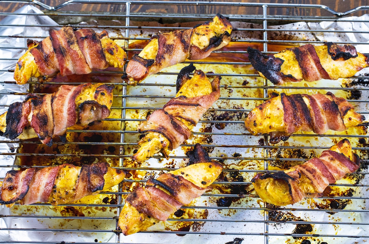 Chicken tenders wrapped with bacon on a wire rack.