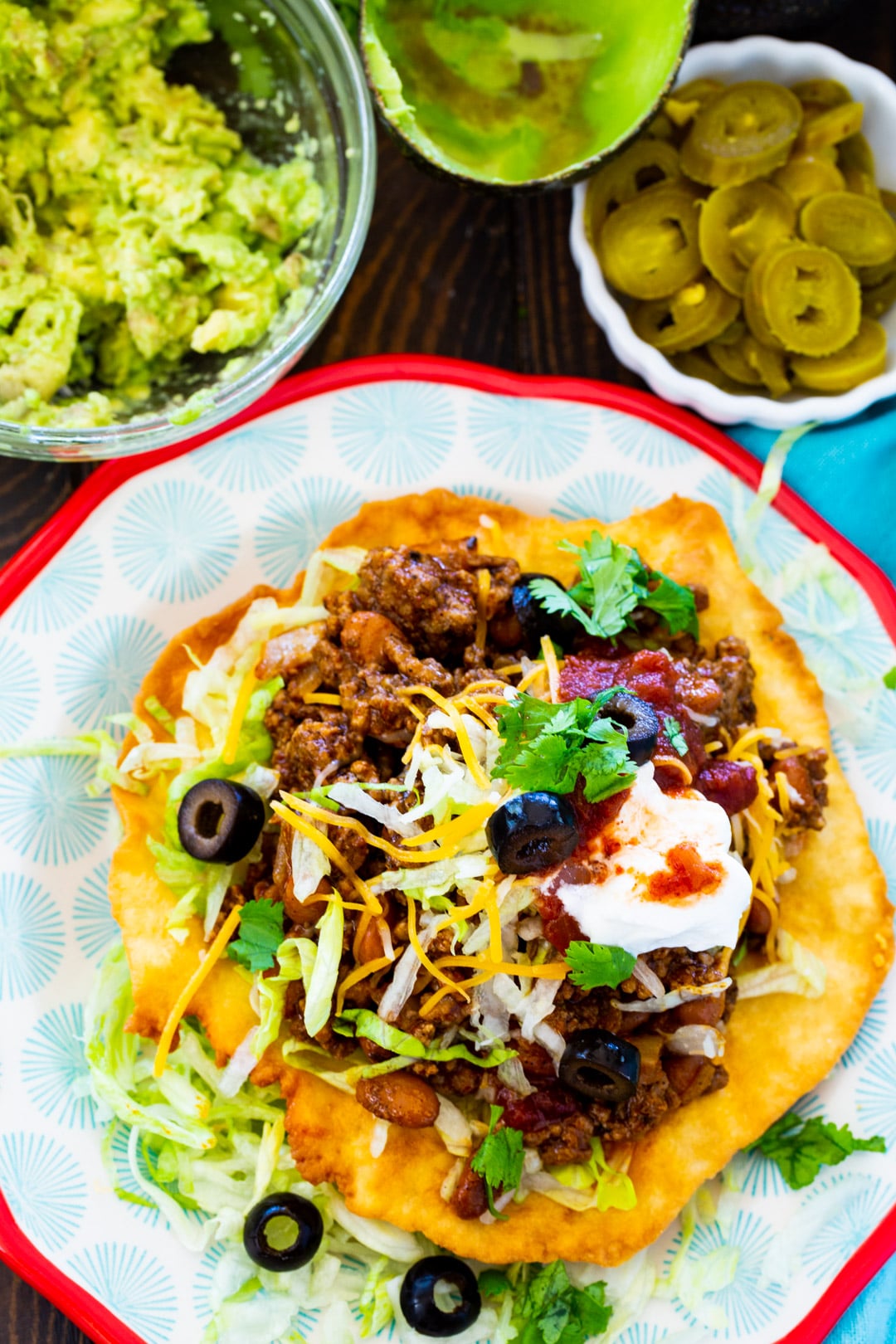 Fry Beef Taco on a plate and bowls of guacamole and pickled jalapenos.