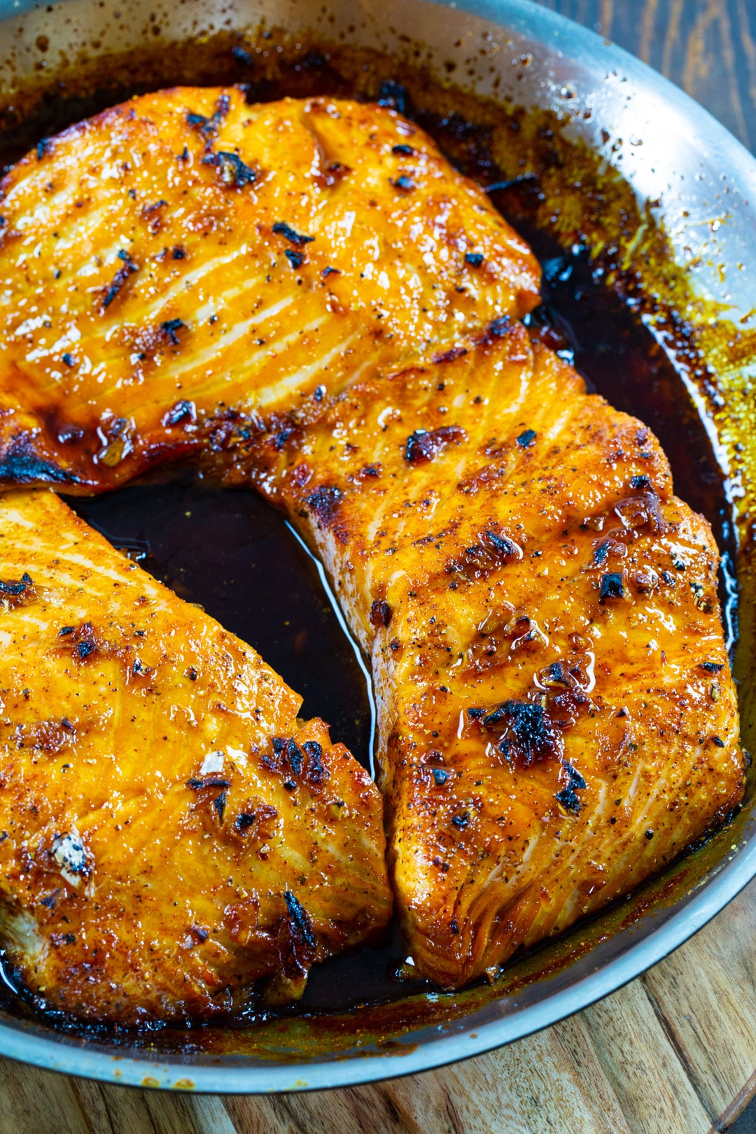 Three salmon fillets in skillet.