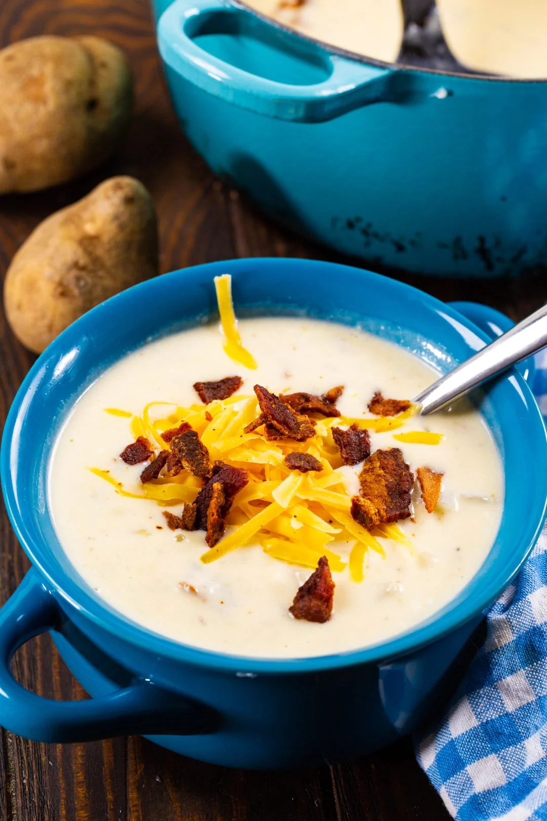 Bacon and Potato Soup topped with cheddar cheese in a serving bowl.