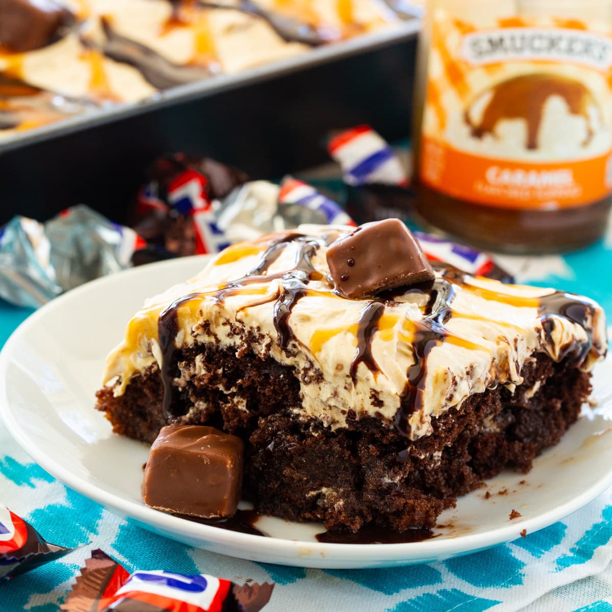 Slice of Snickers Poke Cake on a small plate.