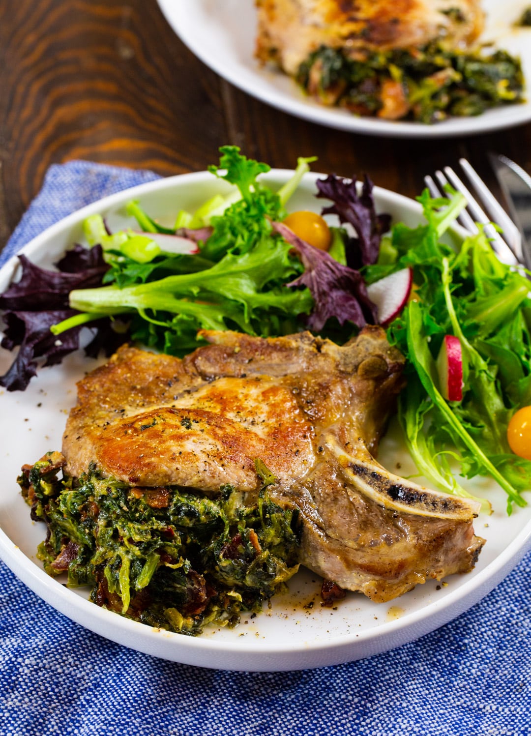 Spinach and Bacon Stuffed Pork Chop on plate with salad.