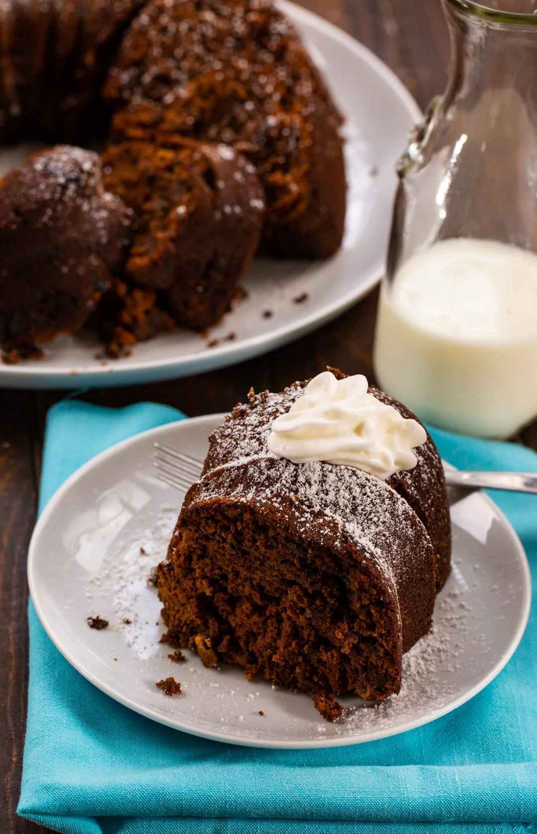 Slice of cake on a plate with rest of cake in background.