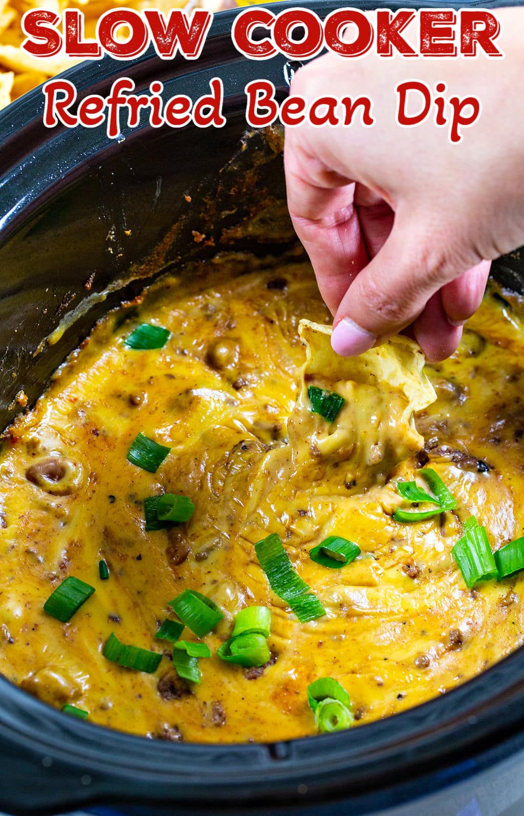 Chip scooping up Refried Bean Dip out of slow cooker.
