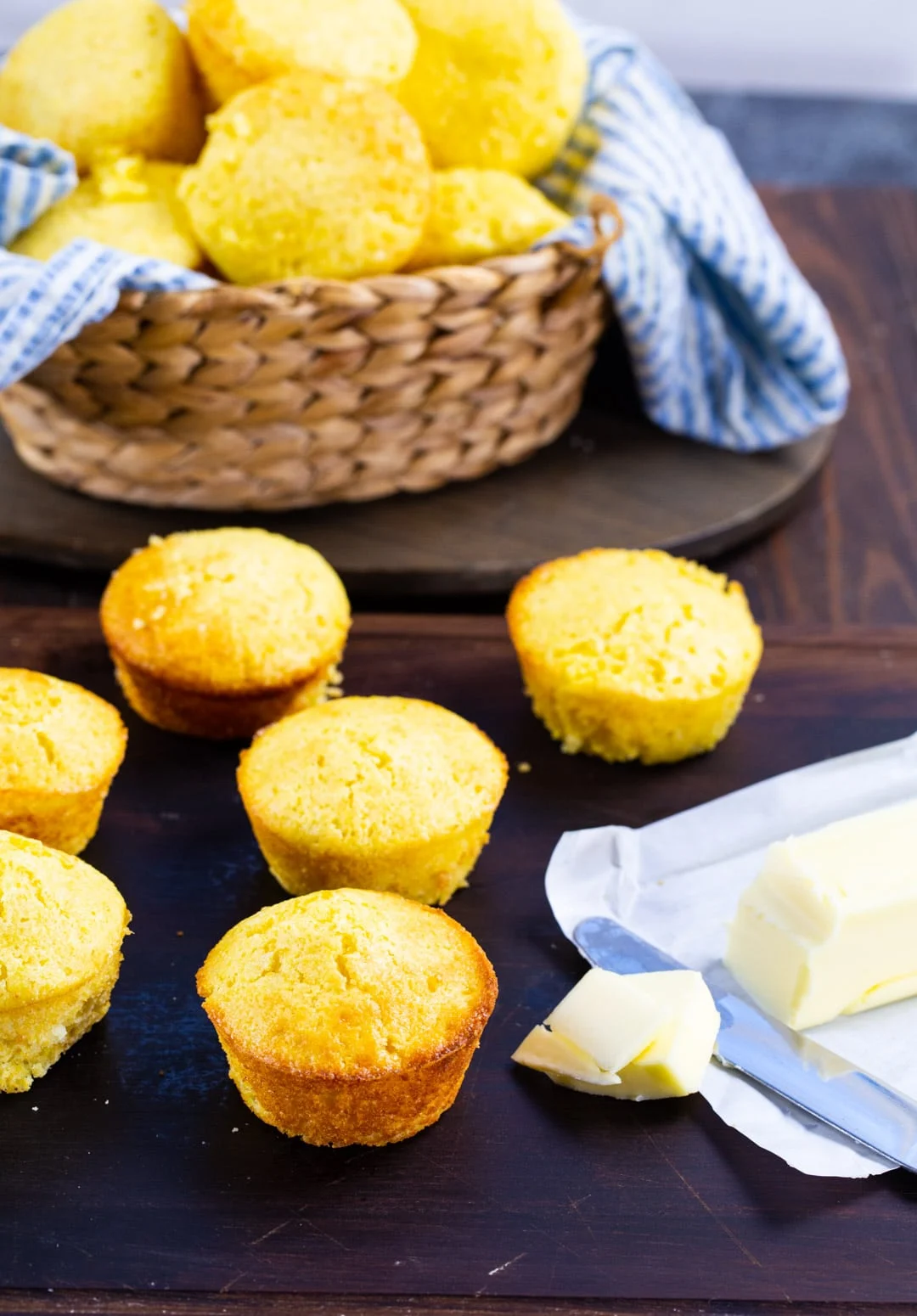 Cornbread muffins on wooden board with stick of butter.