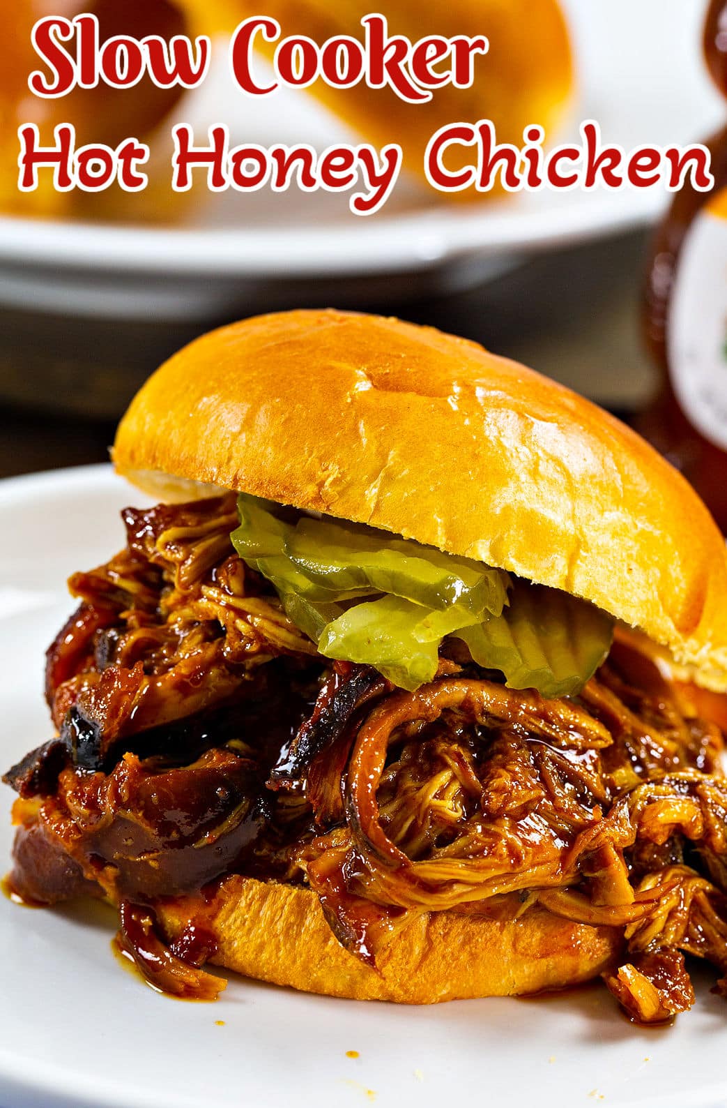 Slow Cooker Hot Honey Chicken on a bun with pickles.
