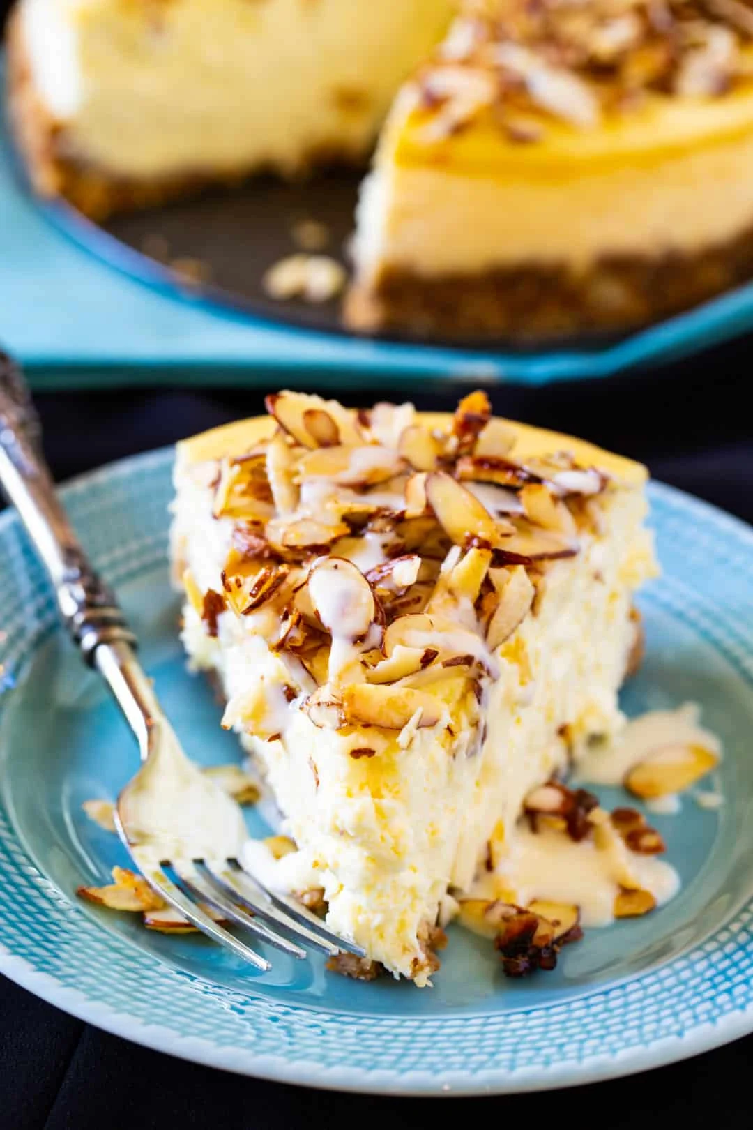 Slice of Amaretto Cheesecake on blue plate.
