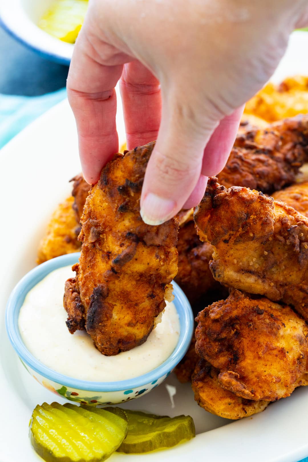 Pickle-Brined Chicken Tenders on plate with small bowl of dipping sauce and pickle slices.