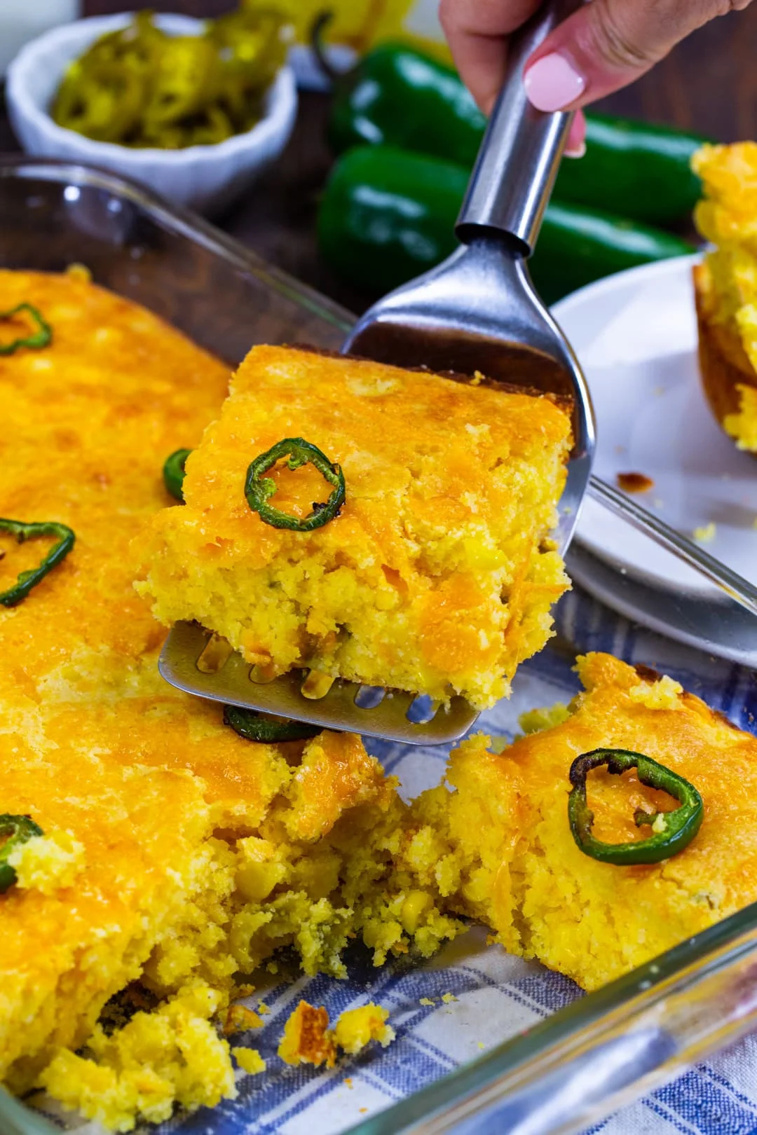 Spatula lifting piece of Texas-Style Jiffy Cornbread out of baking dish.