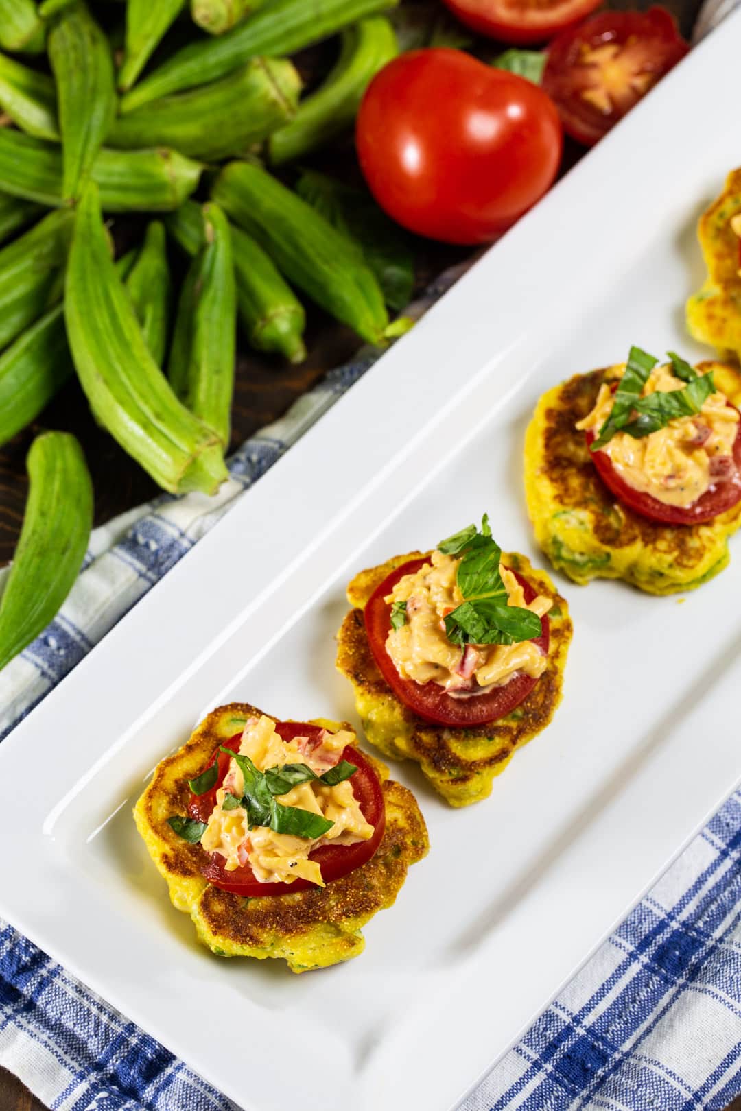 Okra Pancakes with Pimento Cheese on serving plate surrounded by fresh okra.