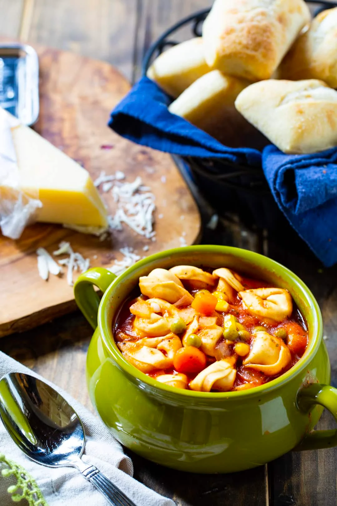 Soup in a bowl and basket of rolls.