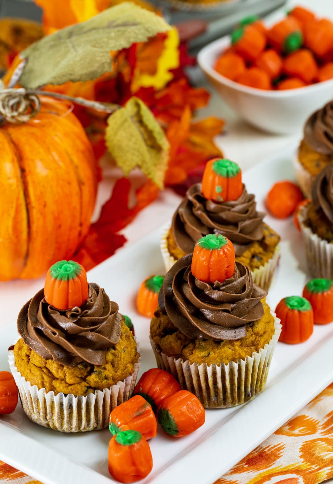 Pumpkin Chocolate Chip Cupcakes surrounded by candy corn pumpkins.
