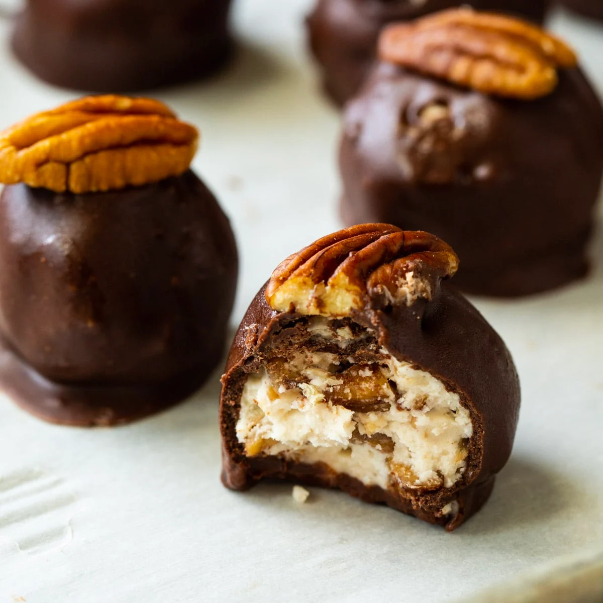 Bourbon Balls covered in chocolate and topped with pecan halves.