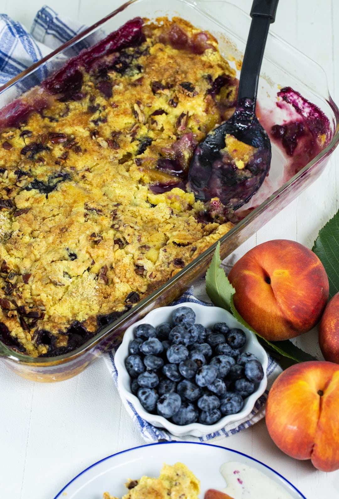 Spoon scooping Blueberry Peach Dump Cake out of baking dish.