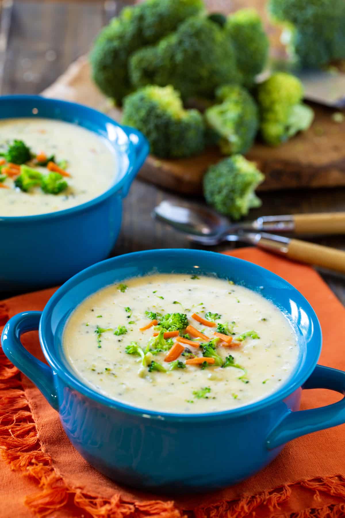 Broccoli soup in a bowl and fresh broccoli in background.