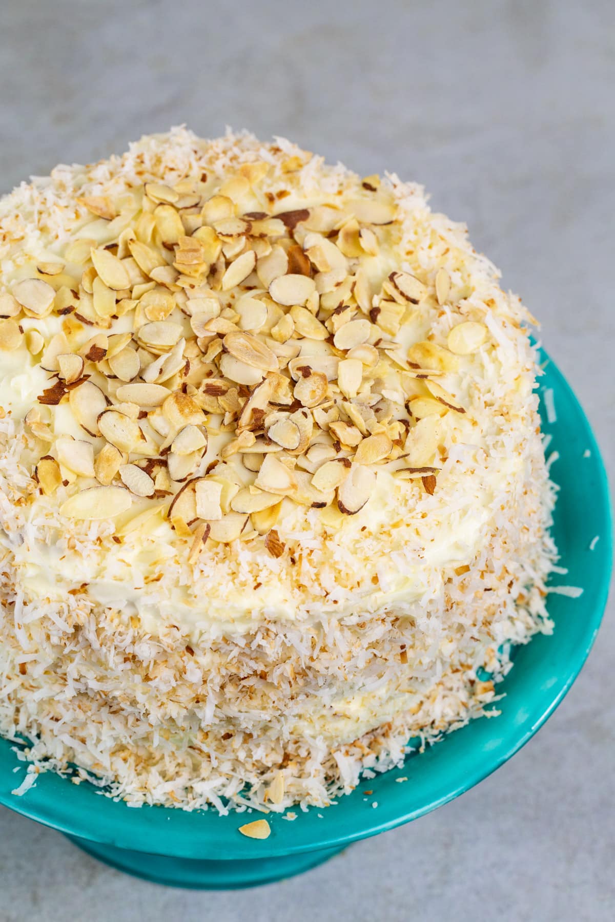 Frosted Cake topped with almond slices on a cake stand.