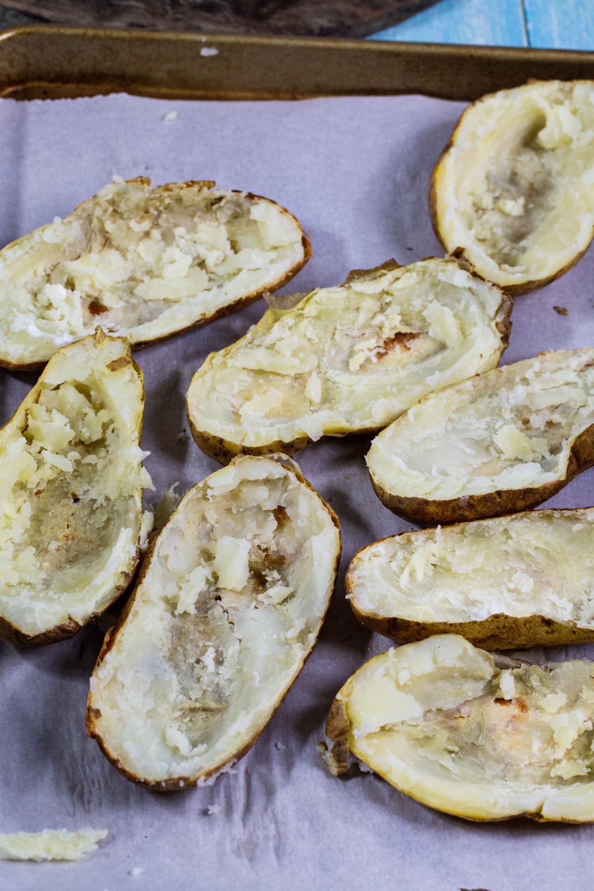 Hollowed out potato halves on baking sheet.