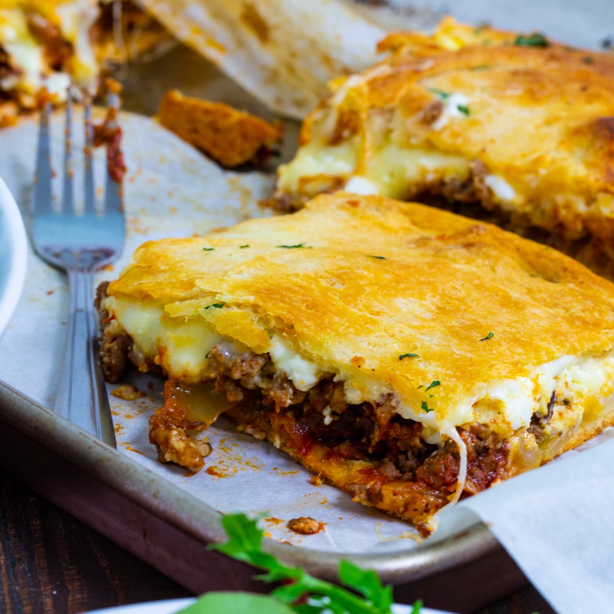 Square of lasagna on baking sheet.