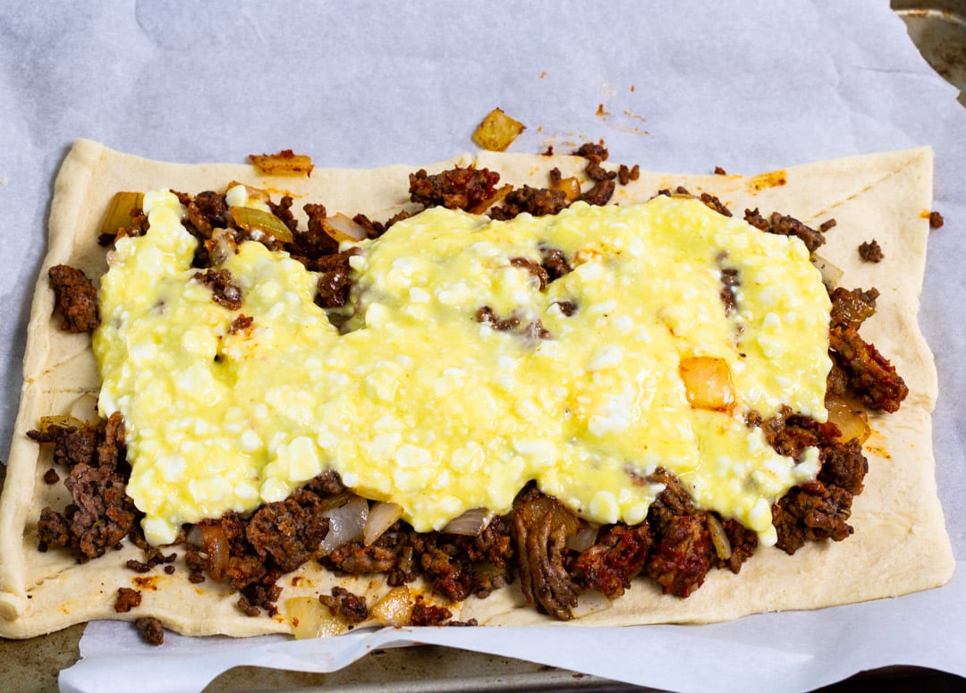 Meat and cheese layer on crescent dough.