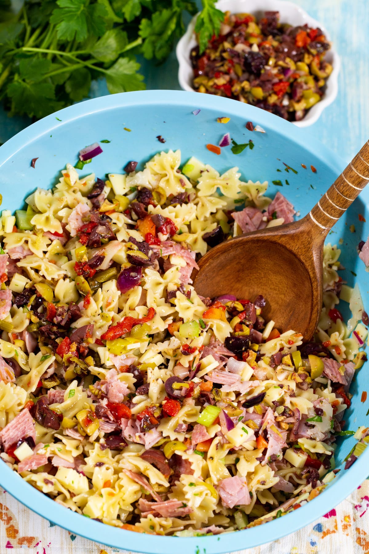 Pasta salad in a mixing bowl and a small bowl of olive salad.
