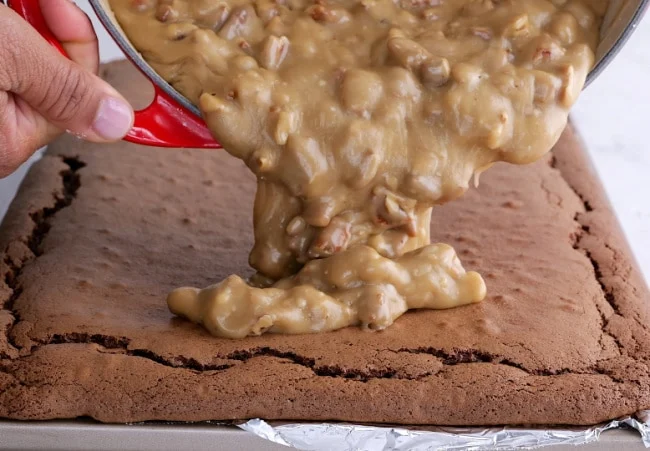Pouring frosting on cake.
