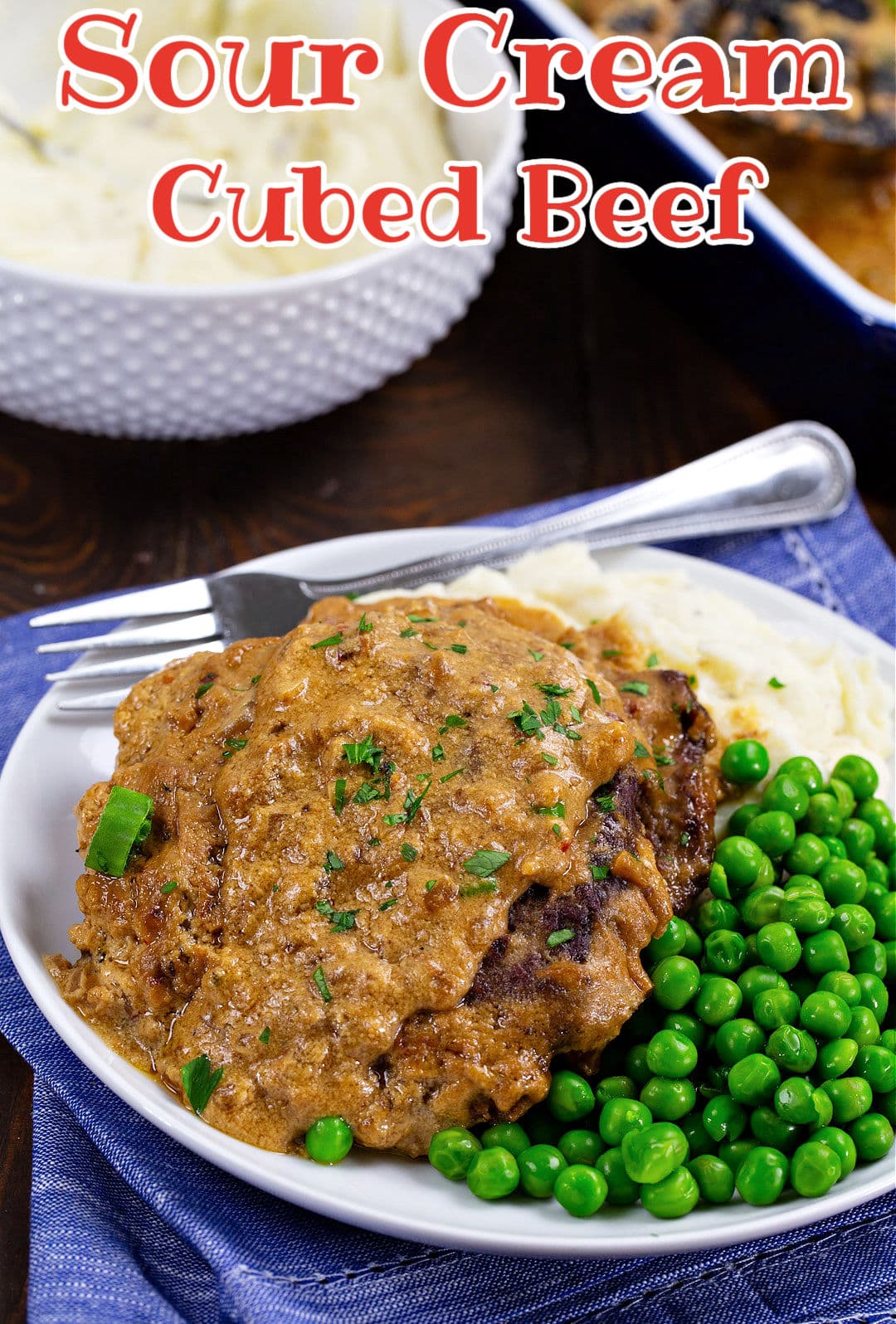 Sour Cream Cubed Beef on plate with peas and mashed potatoes.