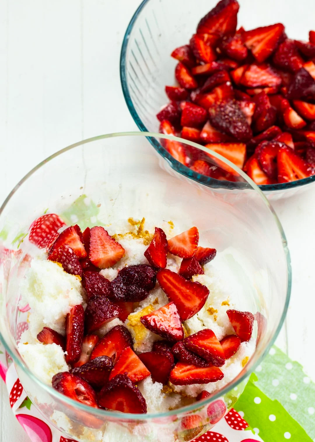 Strawberries layered on top of cake in trifle bowl.
