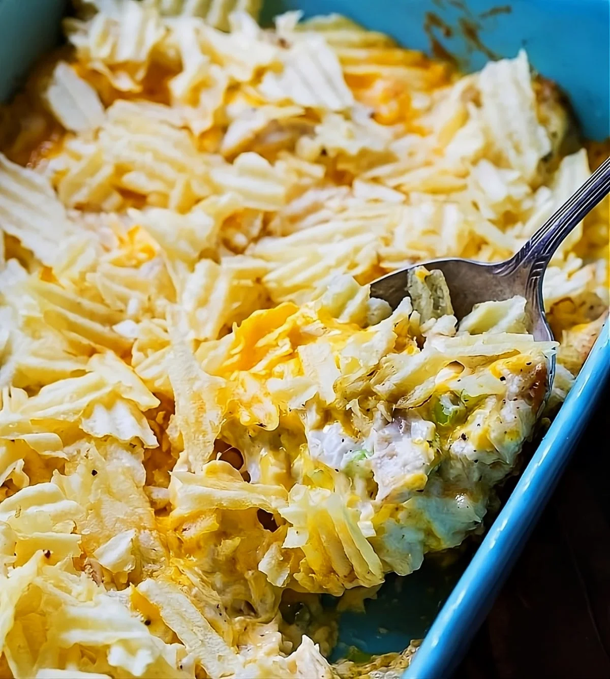 Spoon scooping Hot Chicken Salad out of casserole dish.