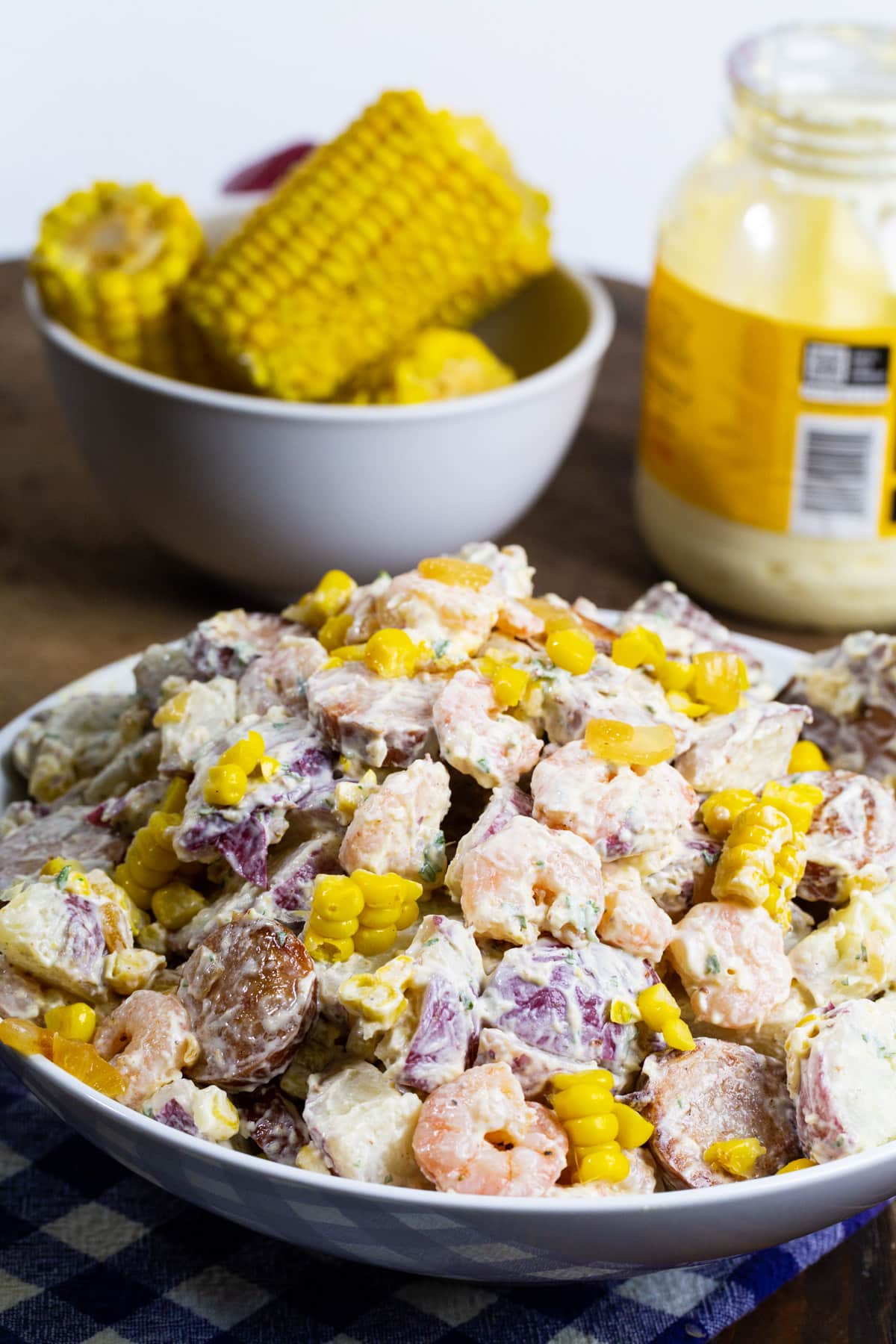 Frogmore Potato Salad in a large bowl with bowl of corn on the cob in background.