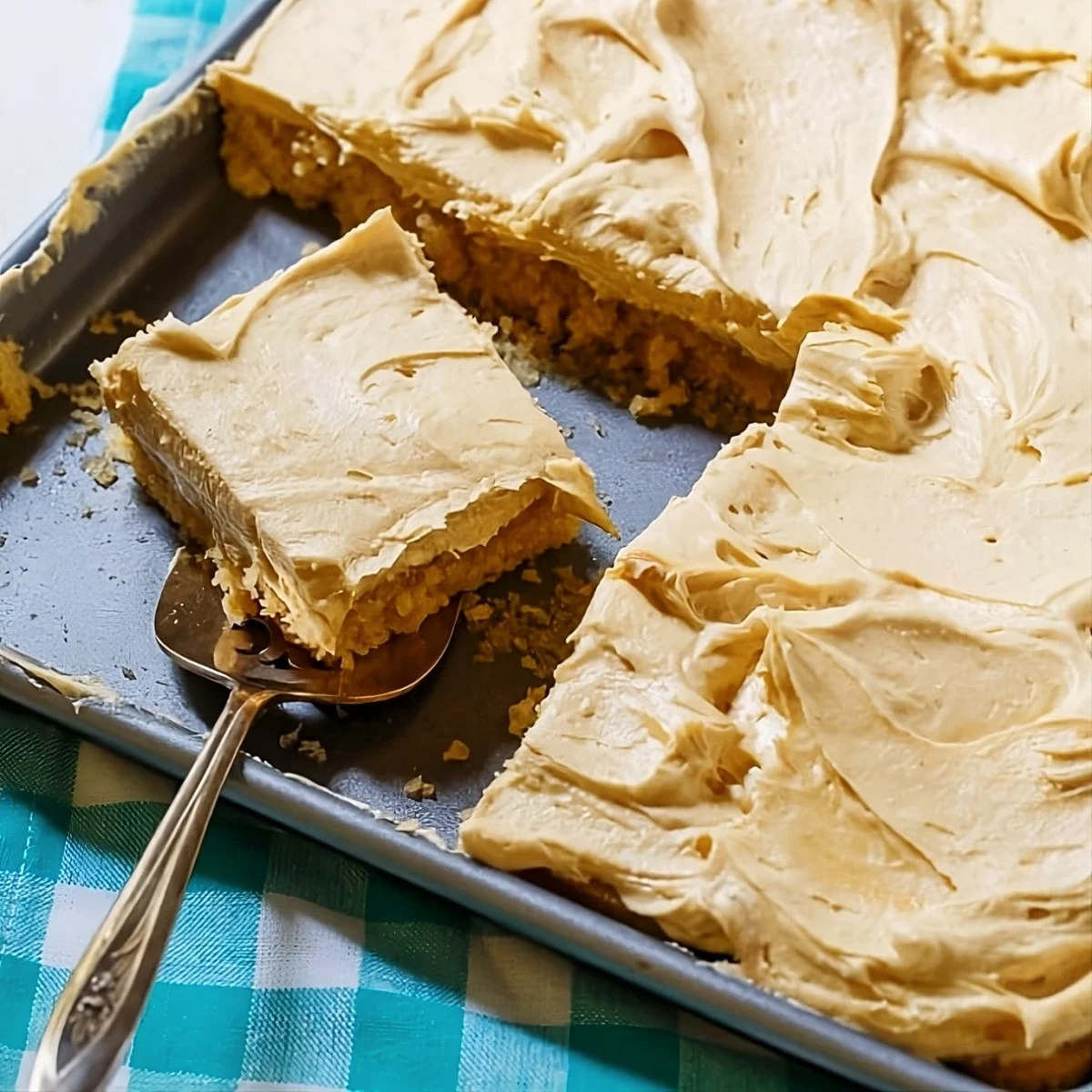 Slice of Peanut Butter Sheet Cake getting lifted out of pan.