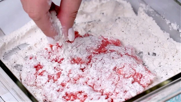 Coating cubed steak in flour.