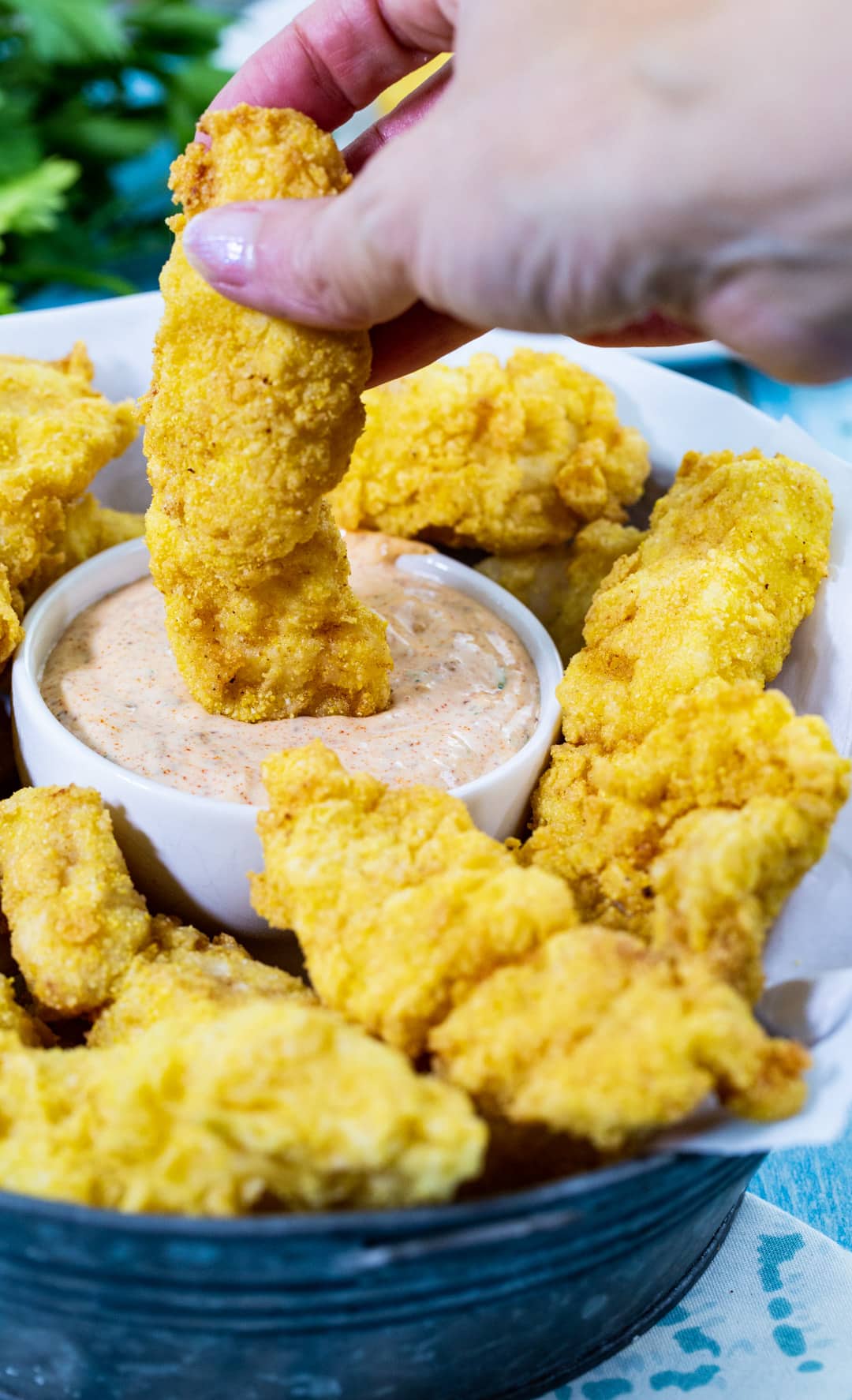 Hand dipping catfish finger into remoulade.