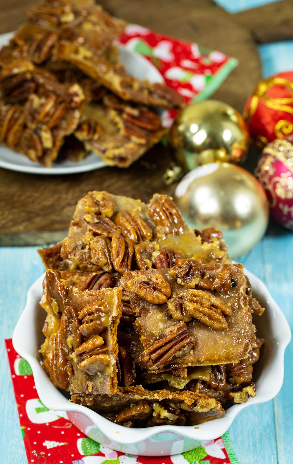 Pieces of Pecan Bark in serving dish and ornaments in background.