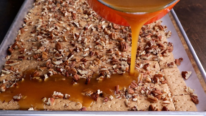 Pouring butter mixture over graham crackers.