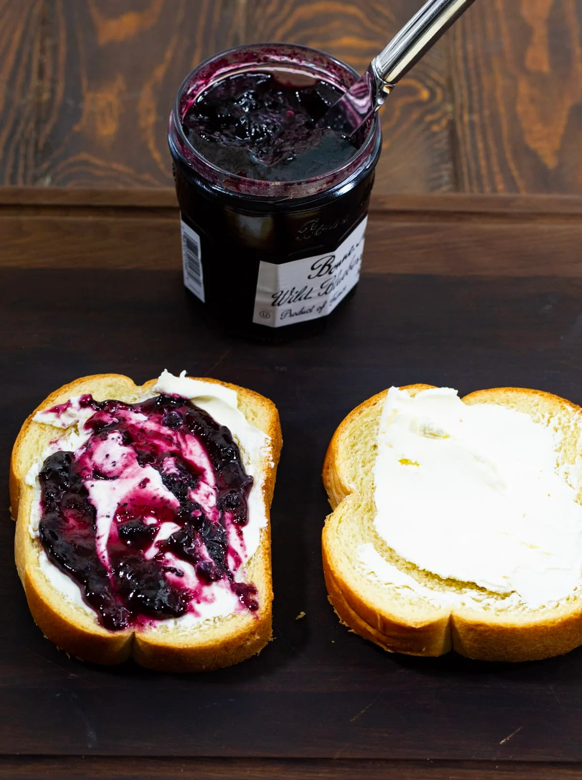 Cream cheese and blueberry preserves spread on bread.