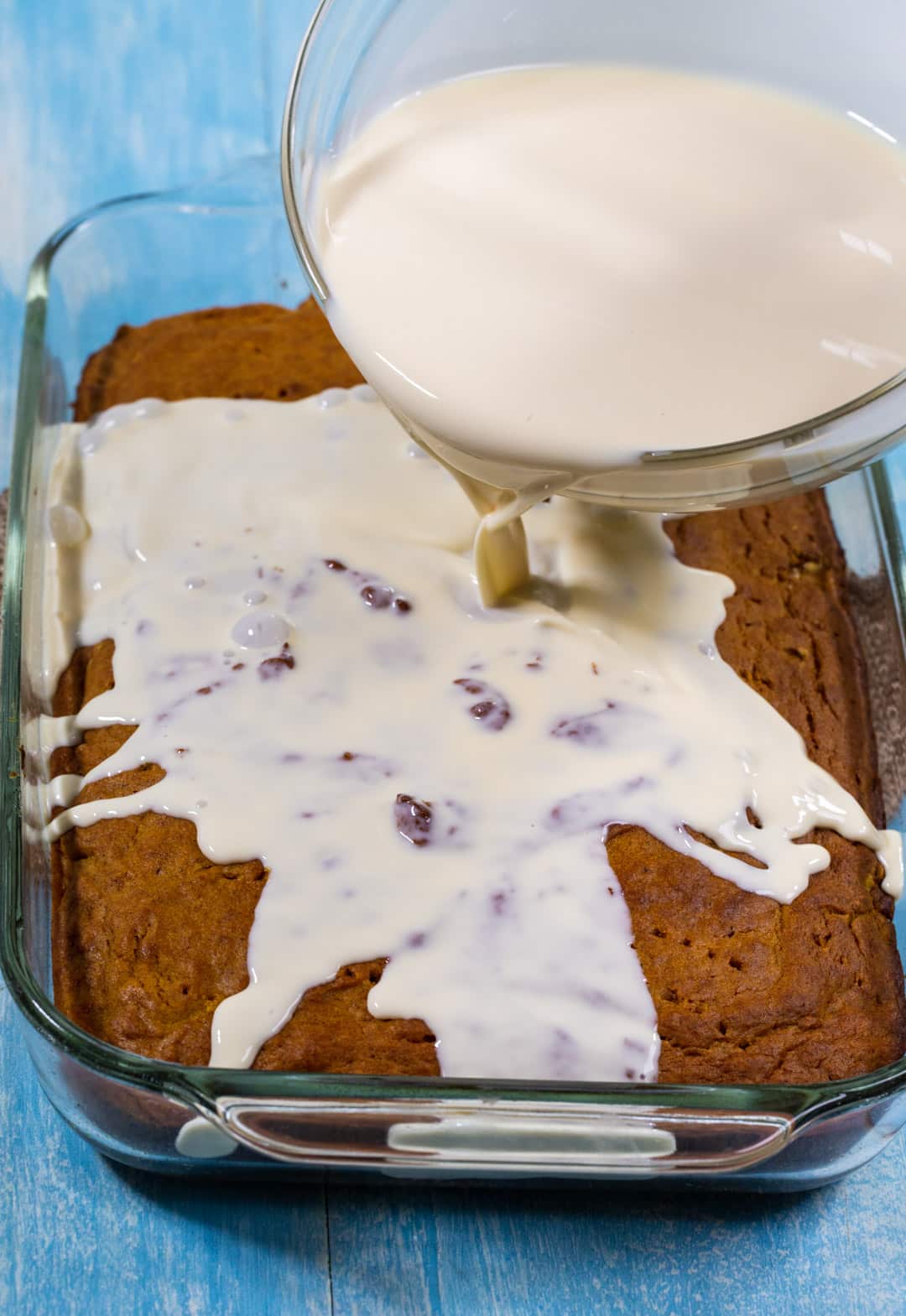 Pouring milk mixture over cake.