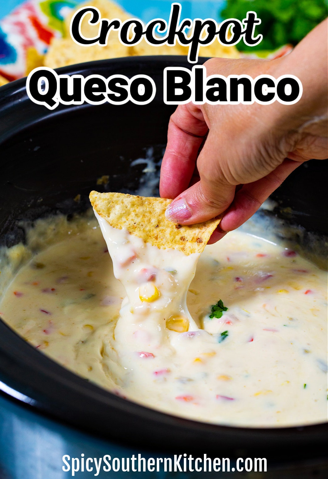 Chip dipping into slow cooker Queso Blanco.