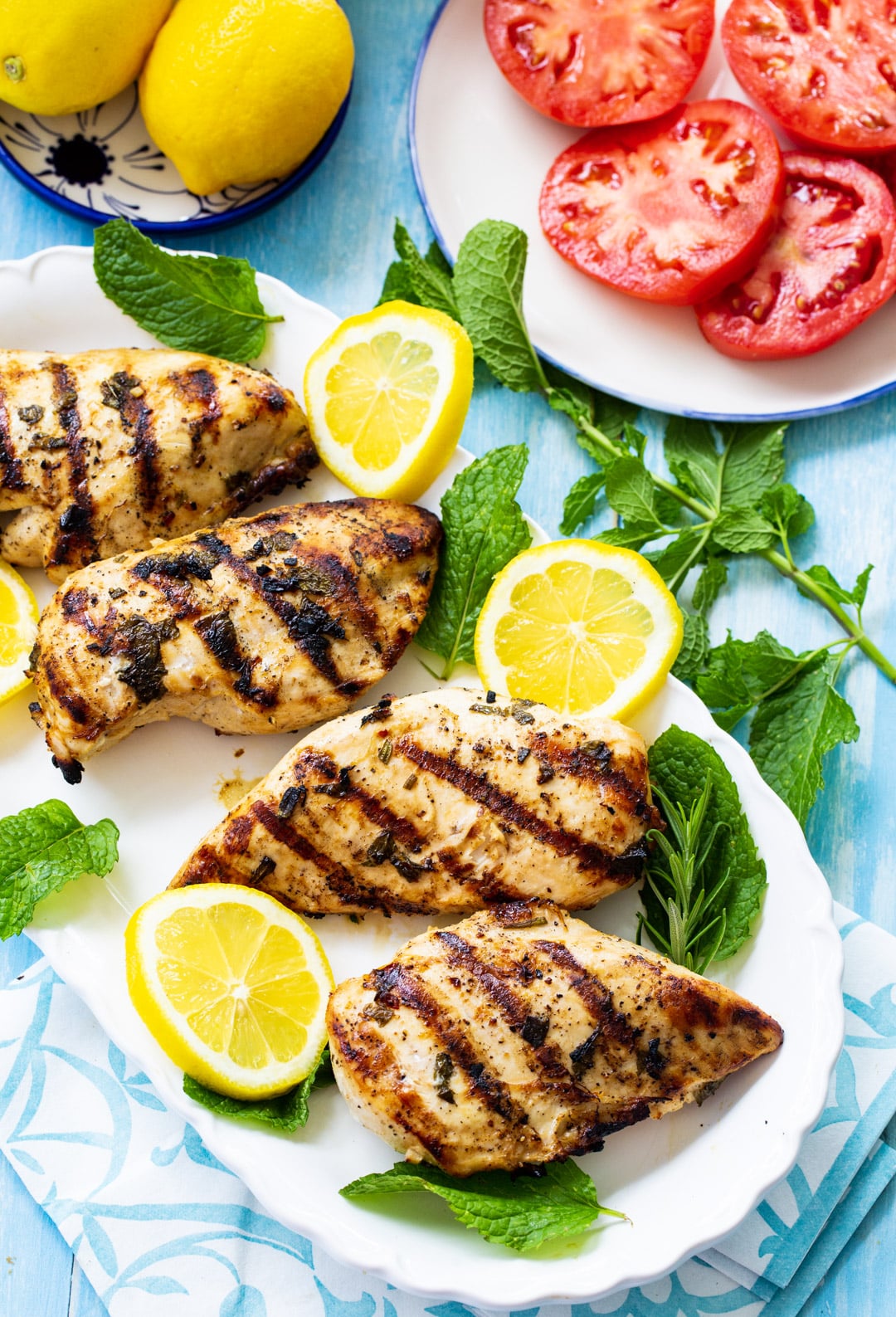 Grilled Chicken on a serving plate with lemon slices and fresh mint.
