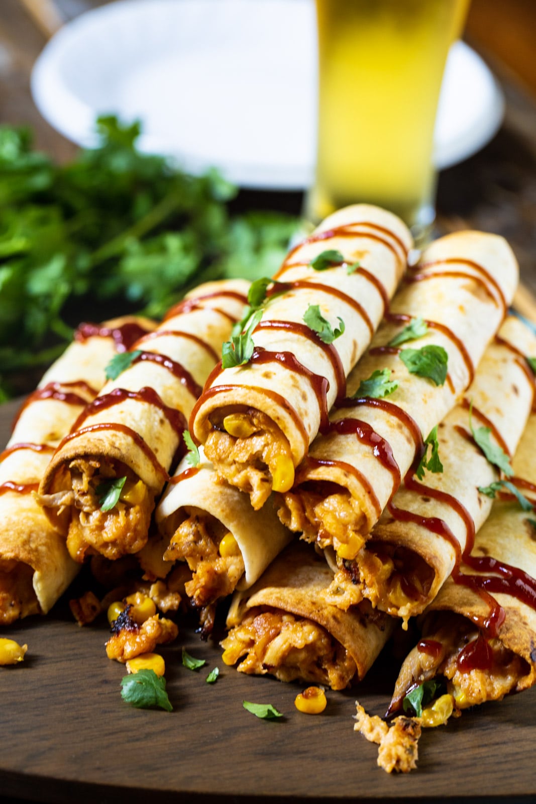 Pile of BBQ Chicken Taquitos and a glass of beer.